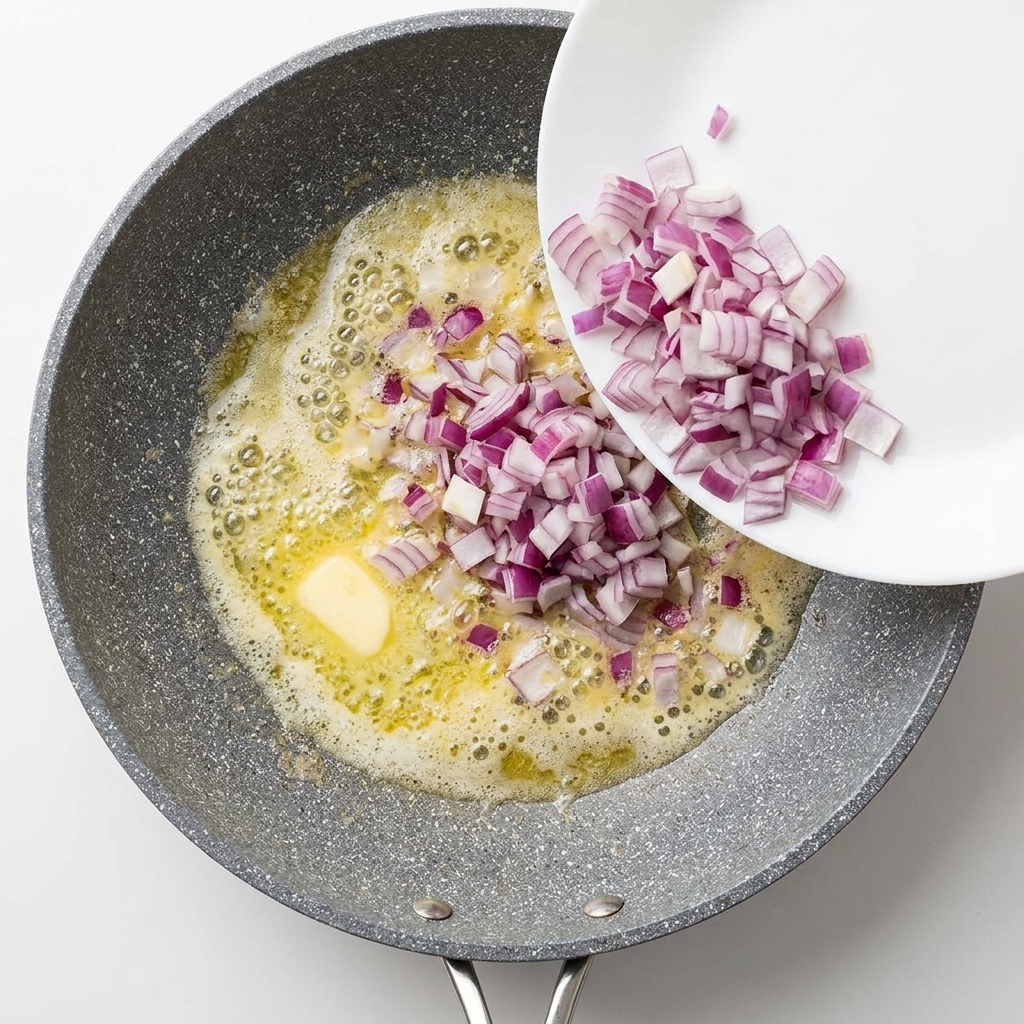 Des dés doignons rouges versés dune assiette blanche dans une poêle bouillonnante de beurre fondu.