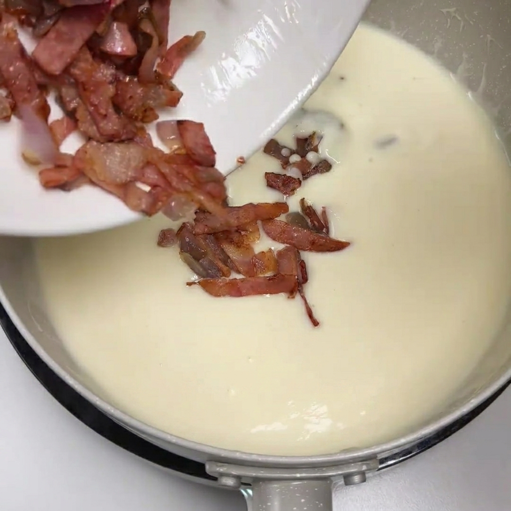 Du bacon et des oignons sautés glissés dune assiette dans la soupe crémeuse aux pommes de terre.
