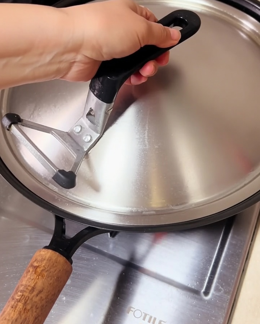 Palourdes cuisant dans un wok couvert, avec de la vapeur séchappant sous le couvercle.