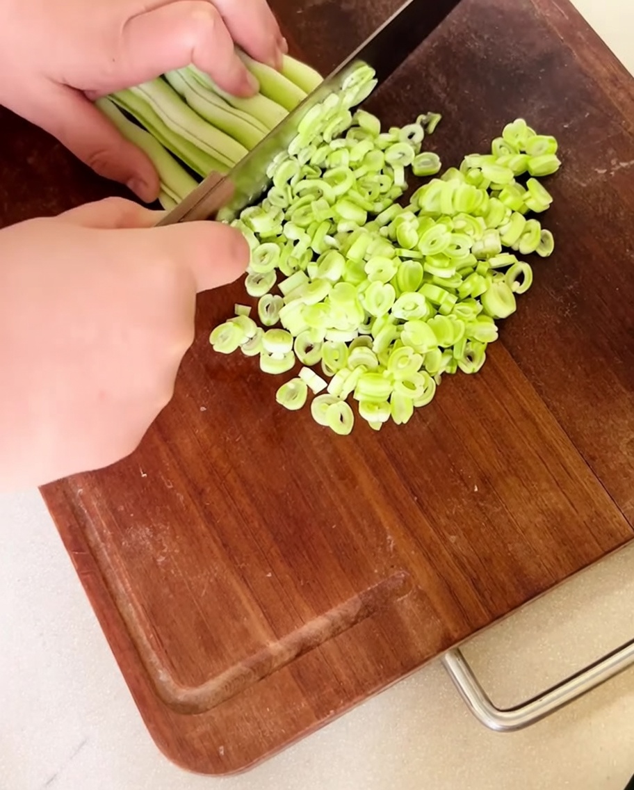Haricots rouges frais finement hachés étalés sur une planche à découper en bois.