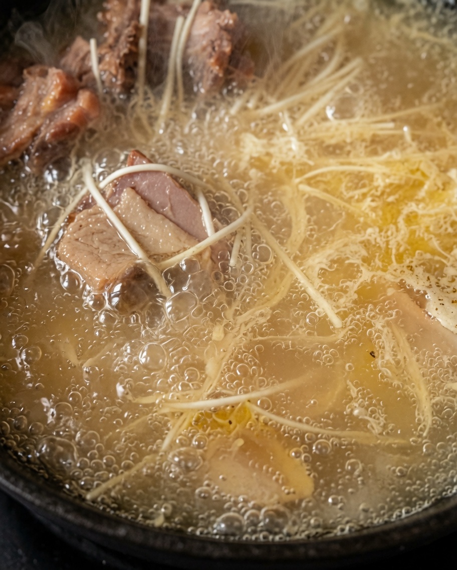Nouilles cuisant dans une marmite bouillonnante de riche soupe de poulet blanche.