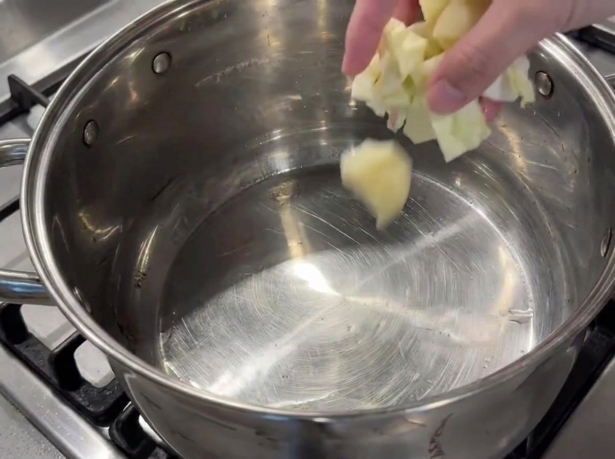 Ajout de légumes hachés dans une grande marmite huilée sur le feu.