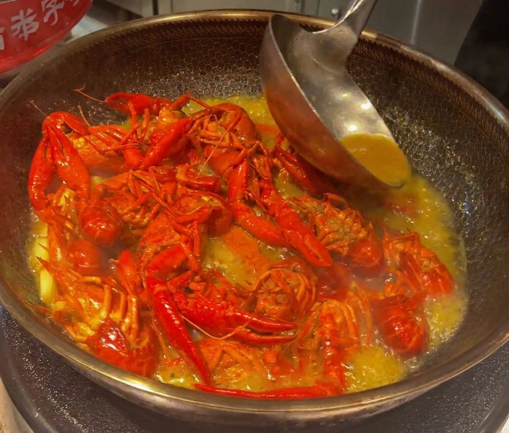 Écrevisses mijotant dans un bouillon réduit et épais dans un wok.
