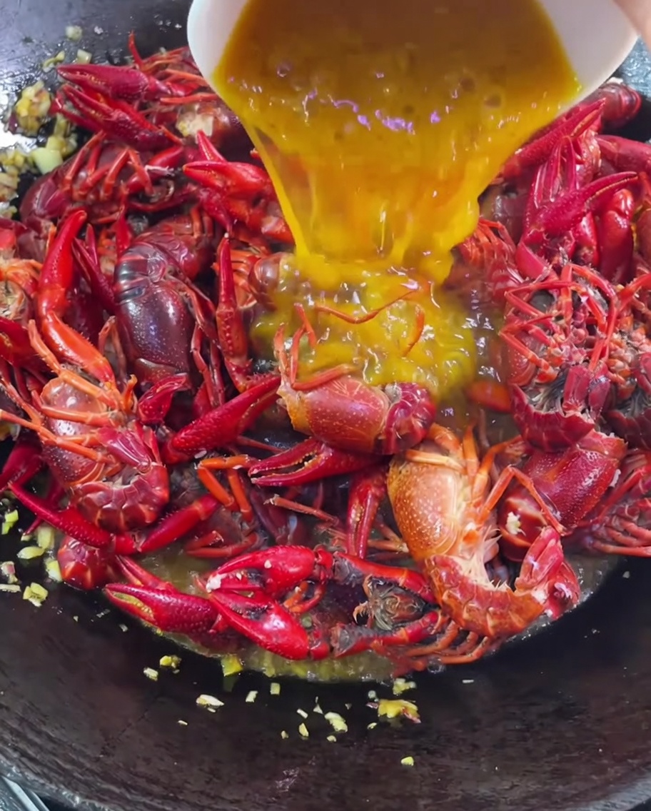 Pâte de citrouille dorée versée sur les écrevisses dans le wok.