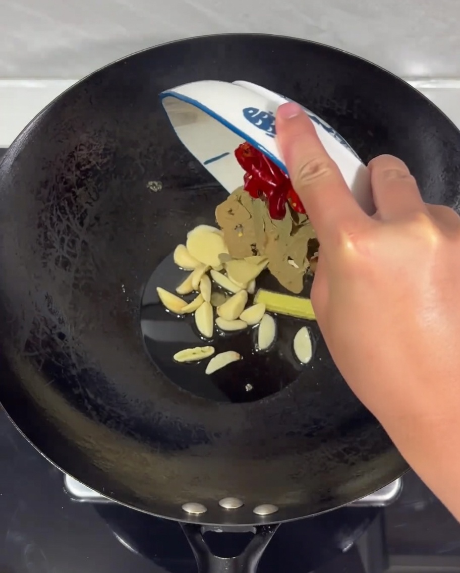Mélange de gingembre, dail et de piments séchés grésillant dans lhuile chaude du wok.