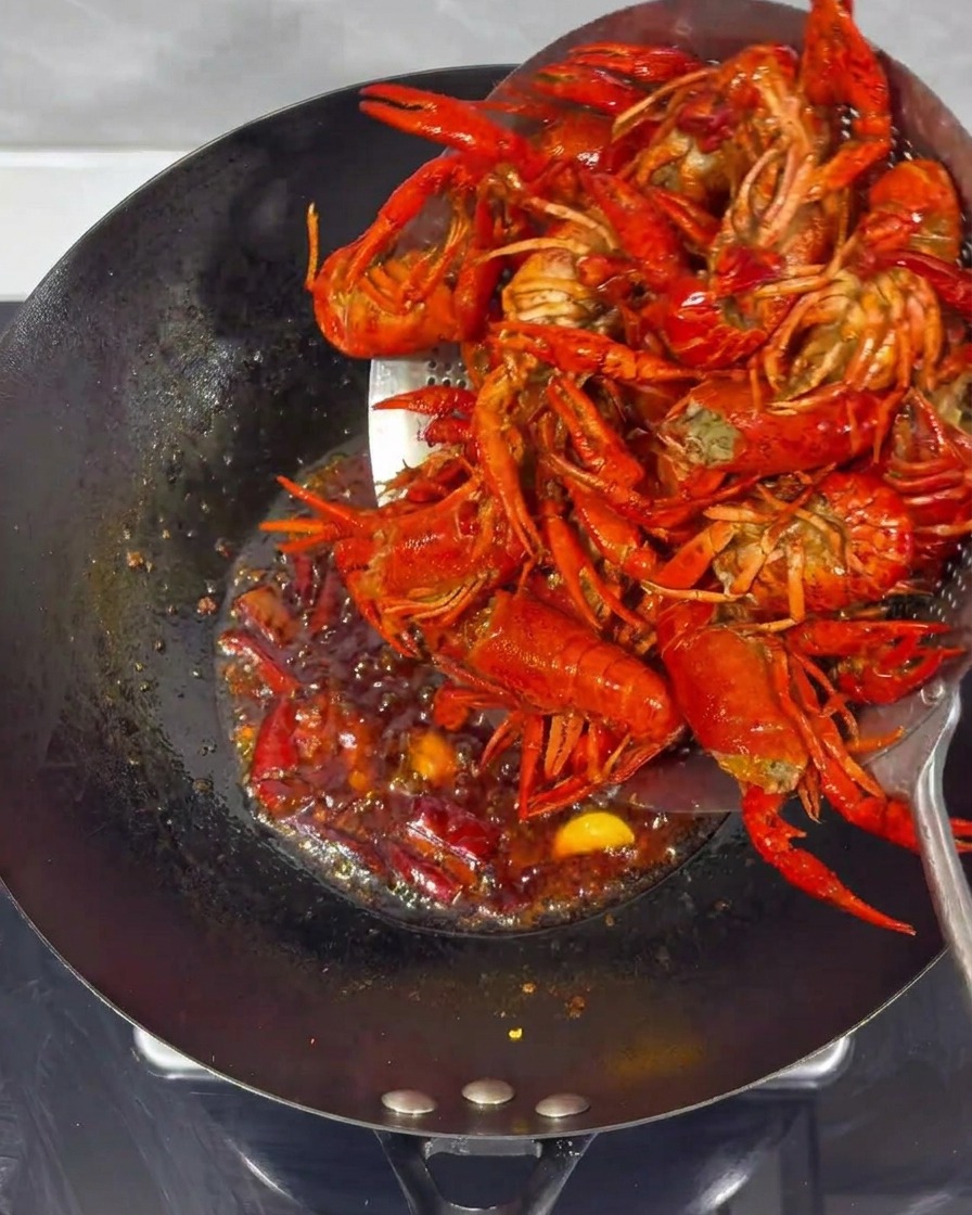 Écrevisses frites mélangées à la sauce épicée dans un wok.