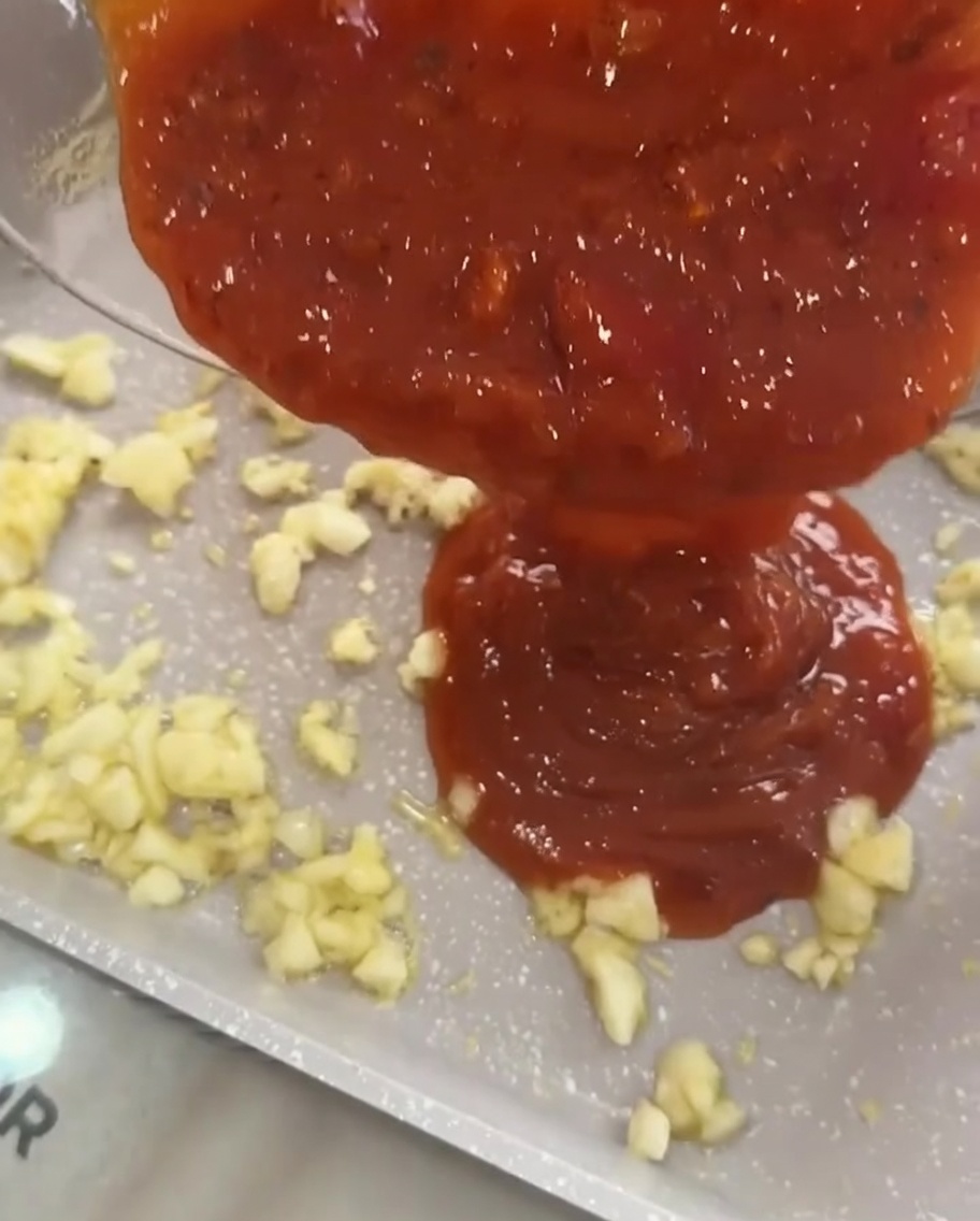 Sauce tomate à la viande versée sur lail revenu dans une poêle.