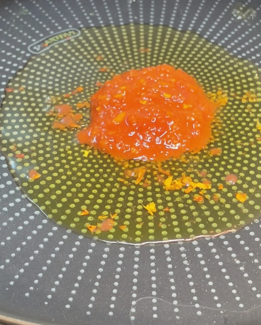 Tomates concassées versées dans lhuile parfumée.