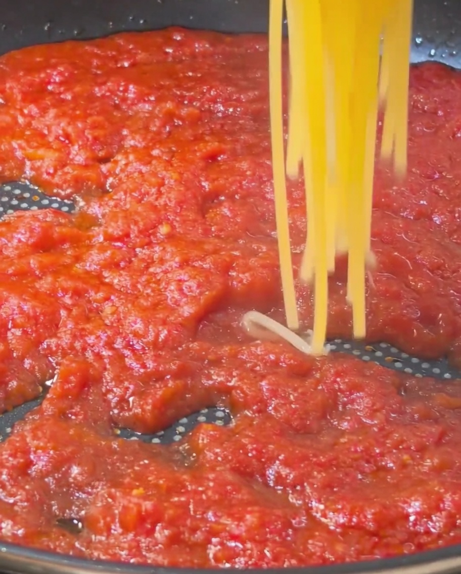 Spaghettis cuits ajoutés à la sauce tomate.