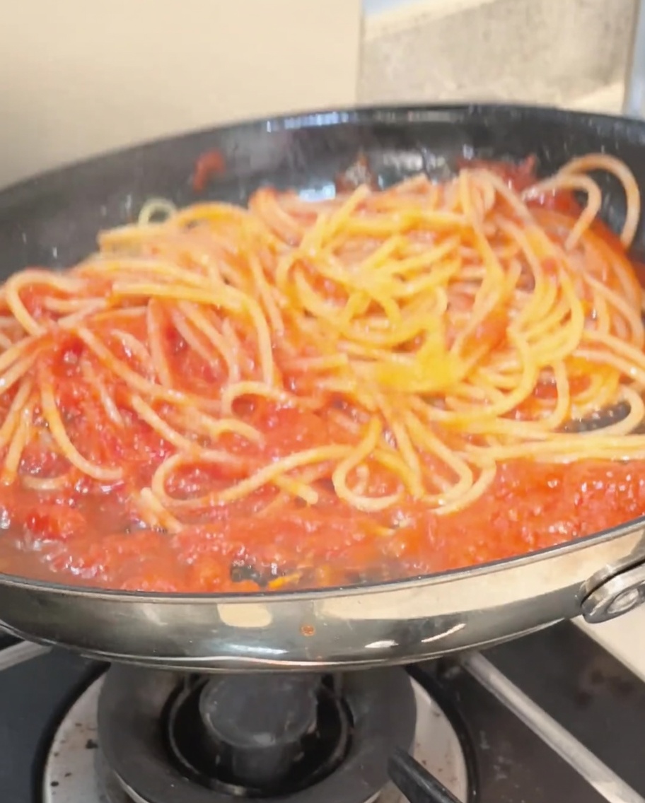 Spaghettis mélangés avec des pinces dans la sauce.