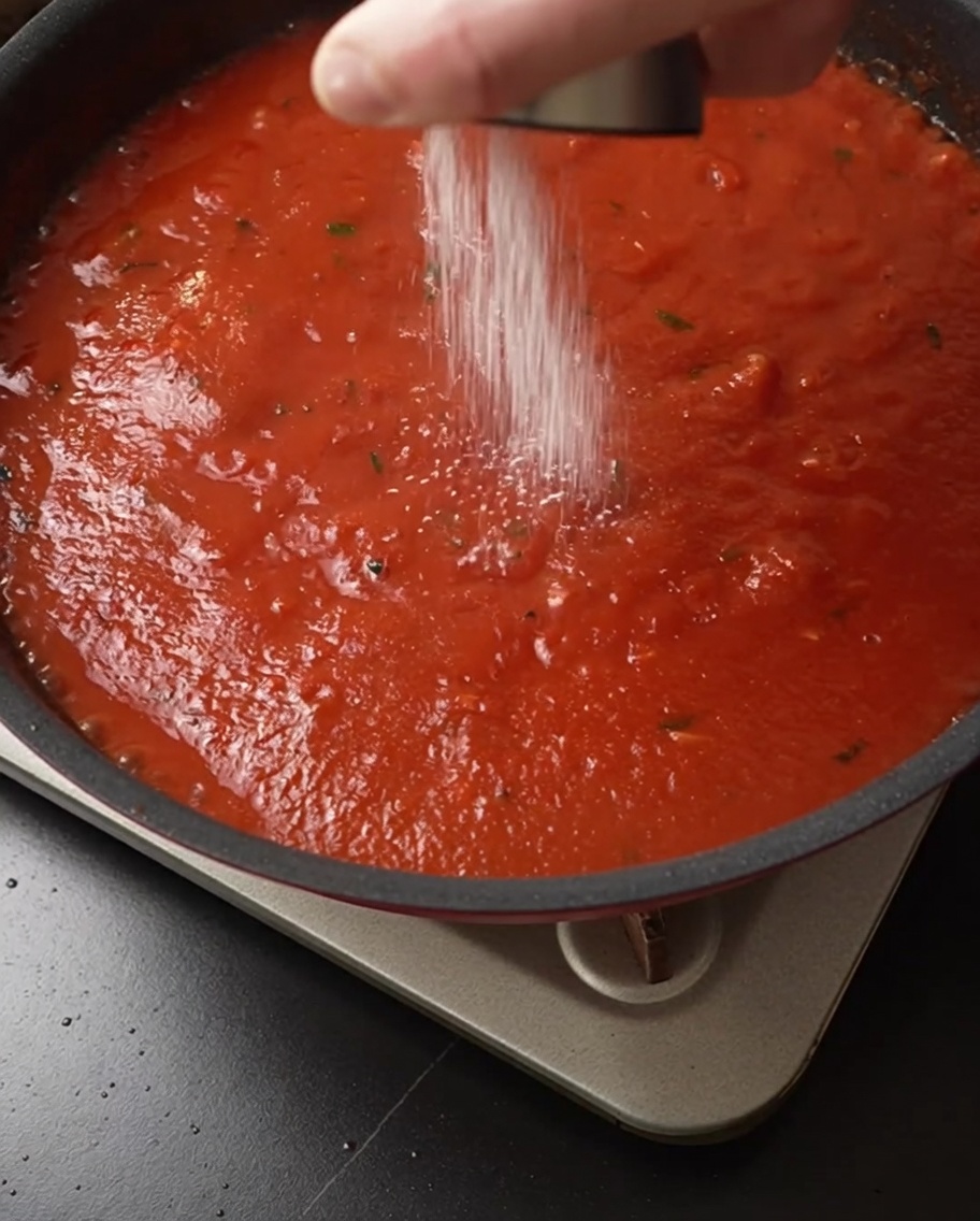 Sel ajouté dans la sauce tomate mijotante.
