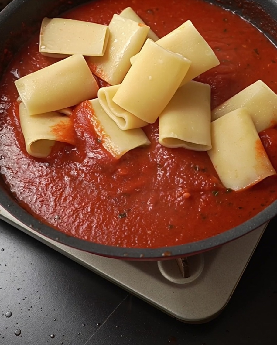 Pâtes cuites ajoutées à la sauce tomate rouge vif.