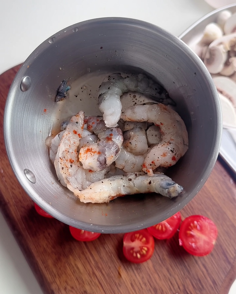Gros plan sur des crevettes crues dans un bol, assaisonnées de poivre, de piment et dun peu de fécule.
