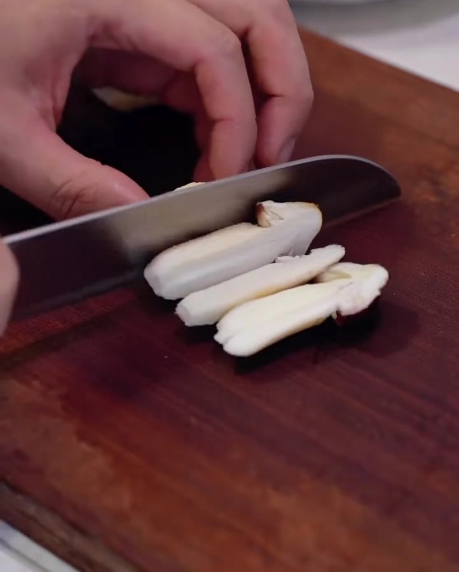 Champignons des pins frais tranchés sur une planche en bois.