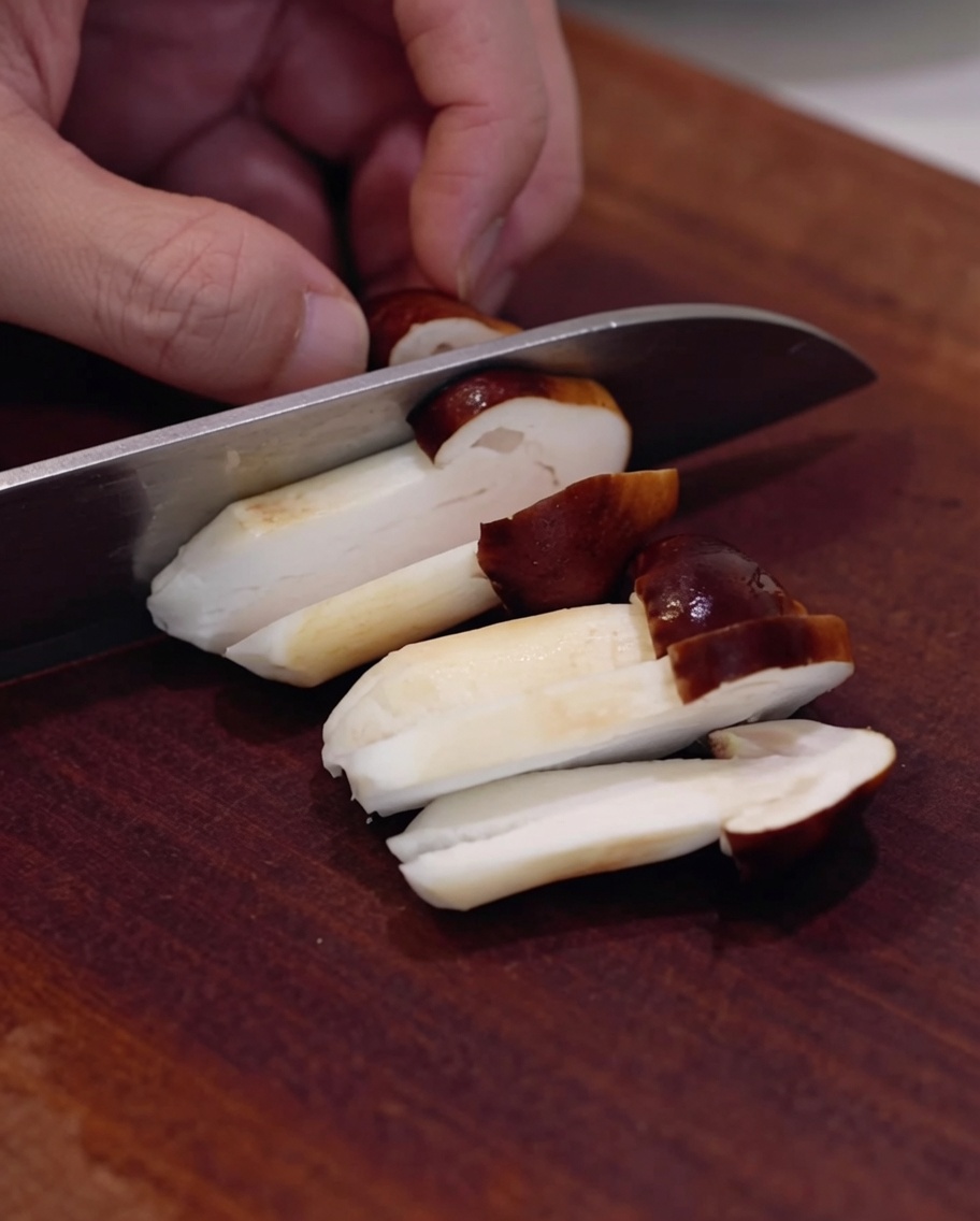 Champignons shiitakés frais tranchés sur une planche en bois.