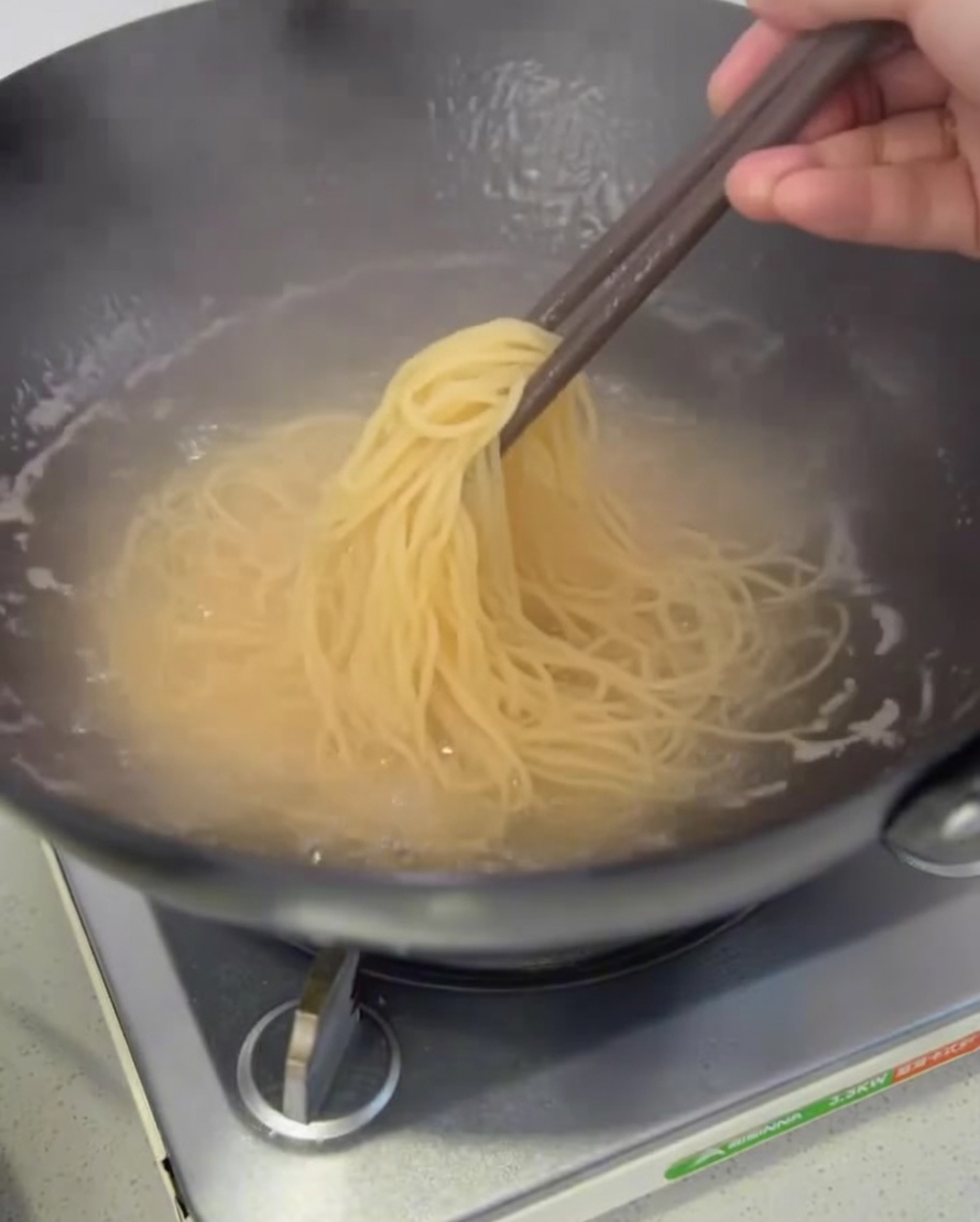 Spaghetti cuits égouttés à laide de baguettes.