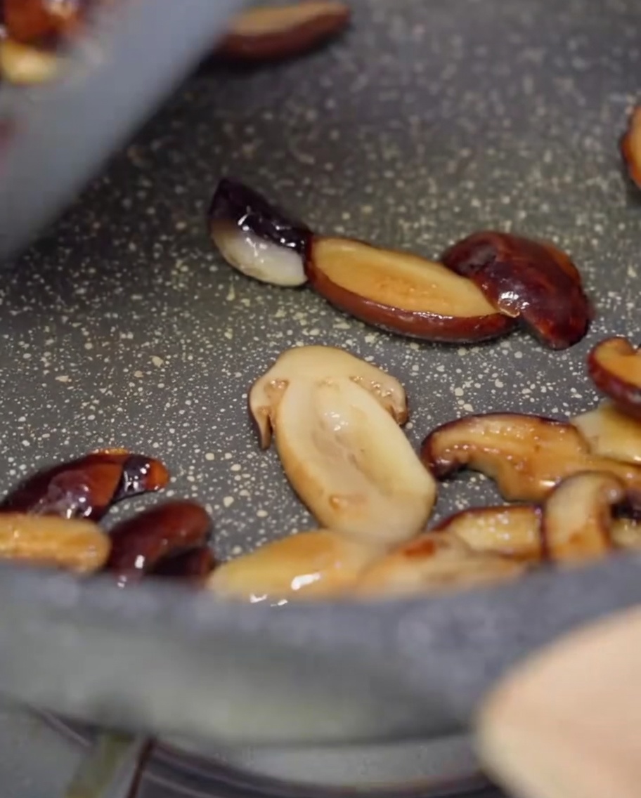 Champignons et lanières de poivrons colorés sautés dans une poêle antiadhésive.