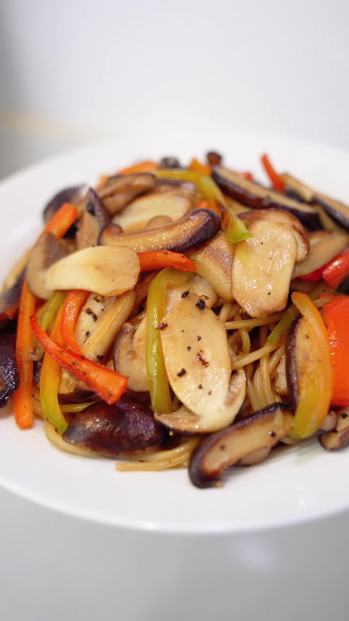 Spaghetti aux champignons au poivre noir servis avec des shiitakés et champignons des pins sautés, des poivrons colorés et du poivre fraîchement moulu.