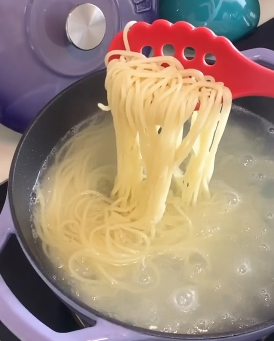 Spaghetti cuits soulevés hors de la casserole avec une pince à pâtes.