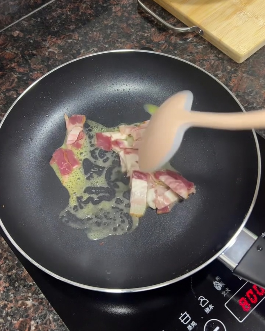 Morceaux de bacon frits dans du beurre fondu dans une poêle.