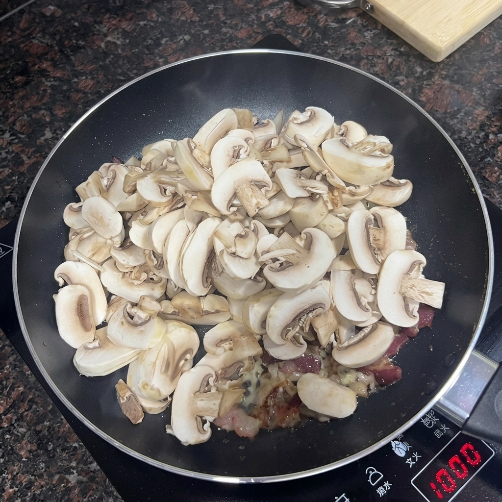 Champignons de Paris émincés ajoutés dans une poêle avec du bacon et de lail.