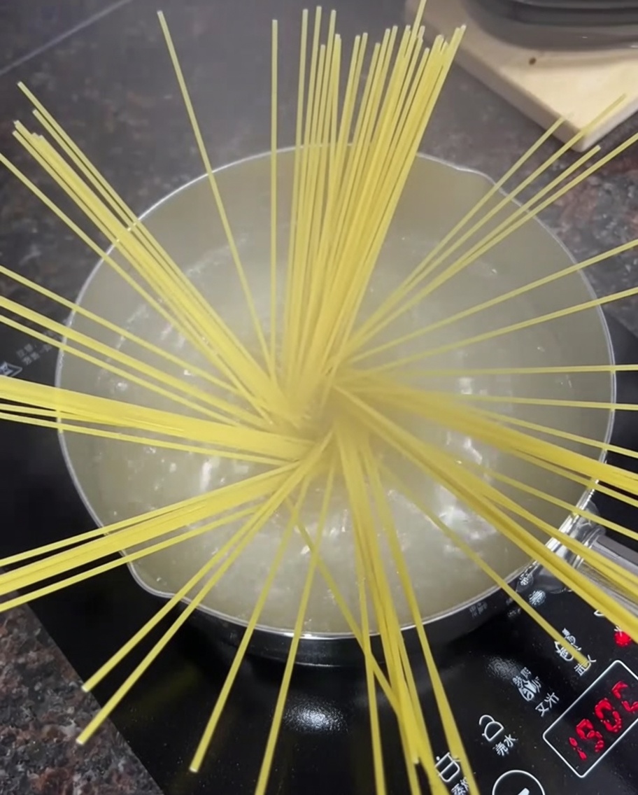 Spaghettis secs dans une casserole deau bouillante sur une cuisinière.