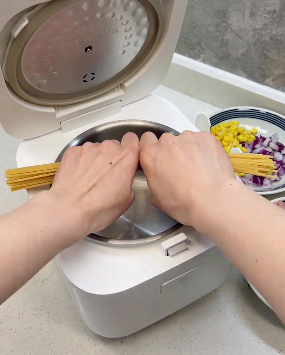 Spaghettis cassés en deux, disposés proprement dans le bol propre du cuiseur à riz.