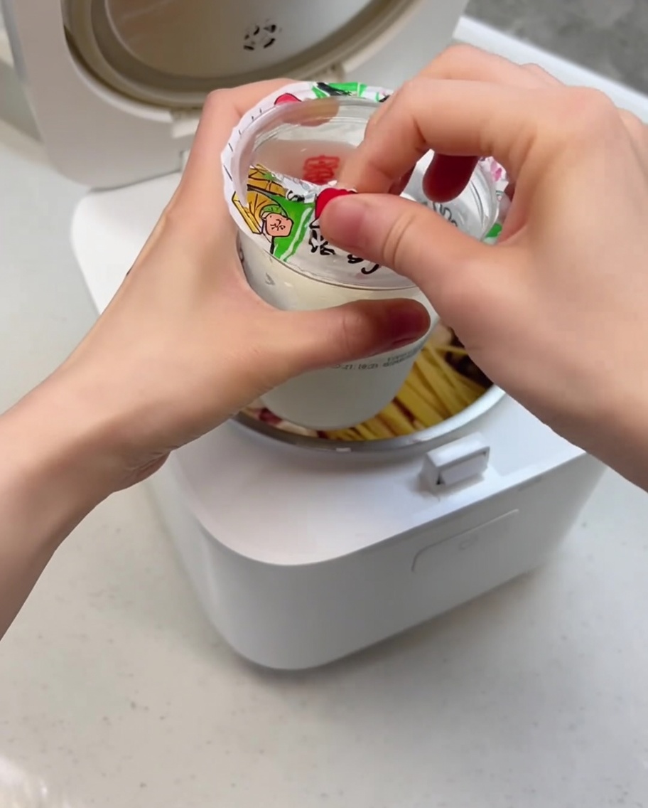 Gros plan montrant la glace fondue versée dans le cuiseur à riz sur les ingrédients.