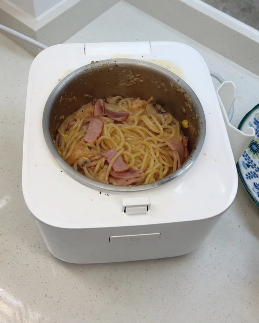 Les spaghettis crémeux aux champignons finis, mélangés avec du fromage et des cubes laitiers dans le cuiseur.