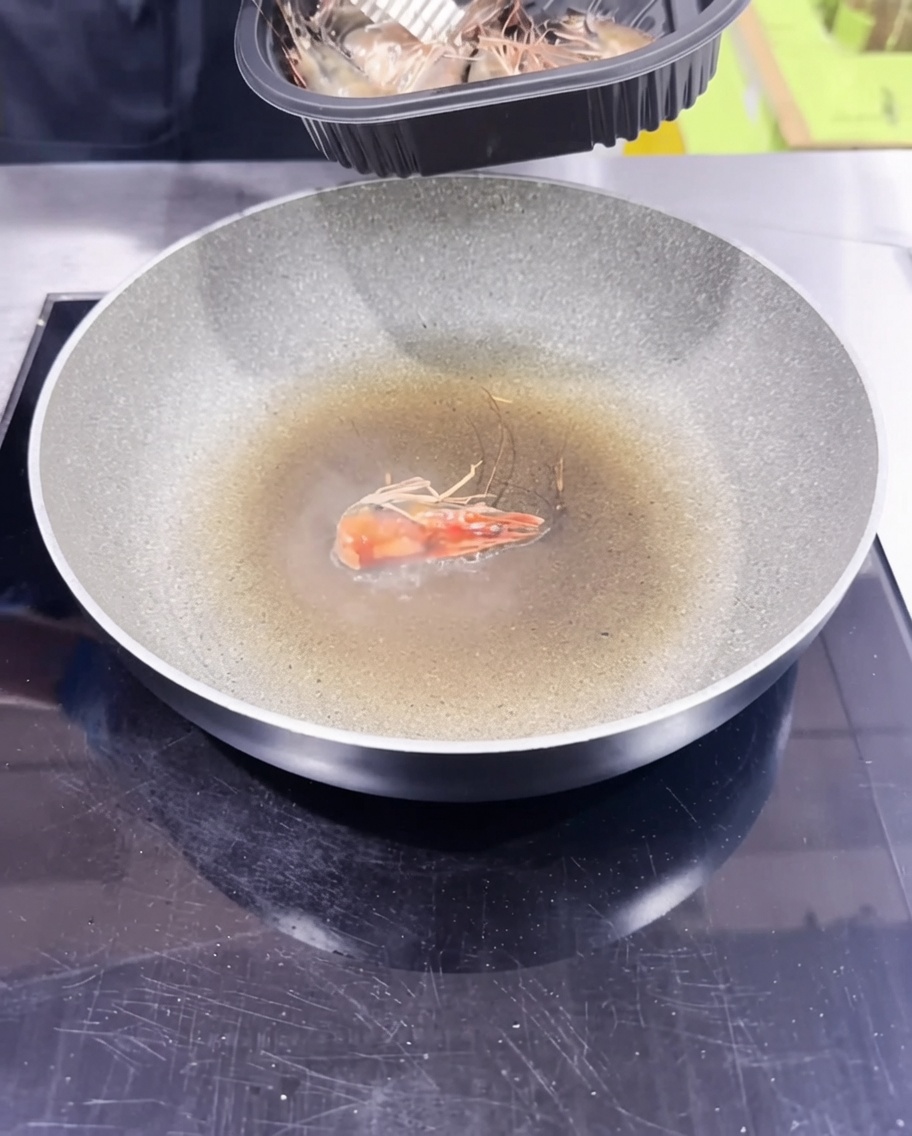 Têtes de crevettes sautées dans une poêle pour créer une huile infusée.