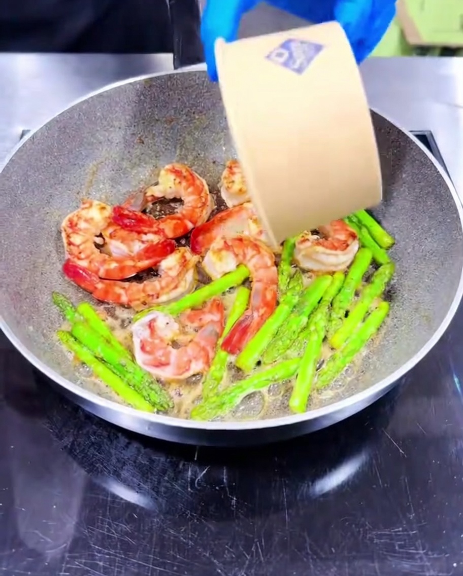 Ail haché ajouté aux crevettes et asperges en cuisson.