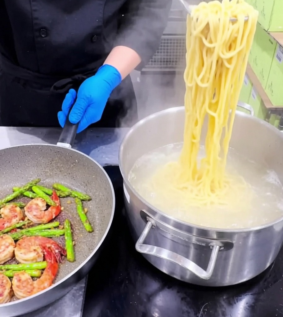 Pâtes ajoutées dans la poêle contenant les crevettes et asperges.
