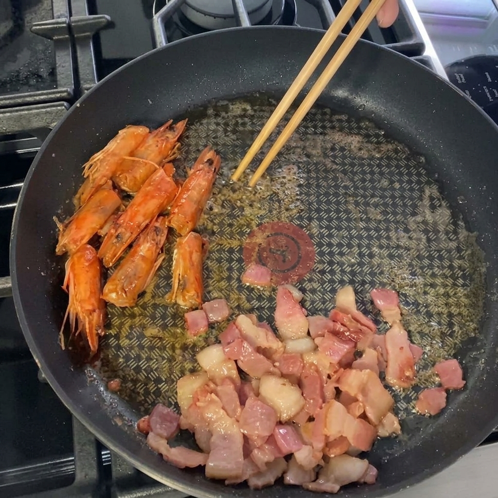 Grosses crevettes placées dans la poêle avec le lard.