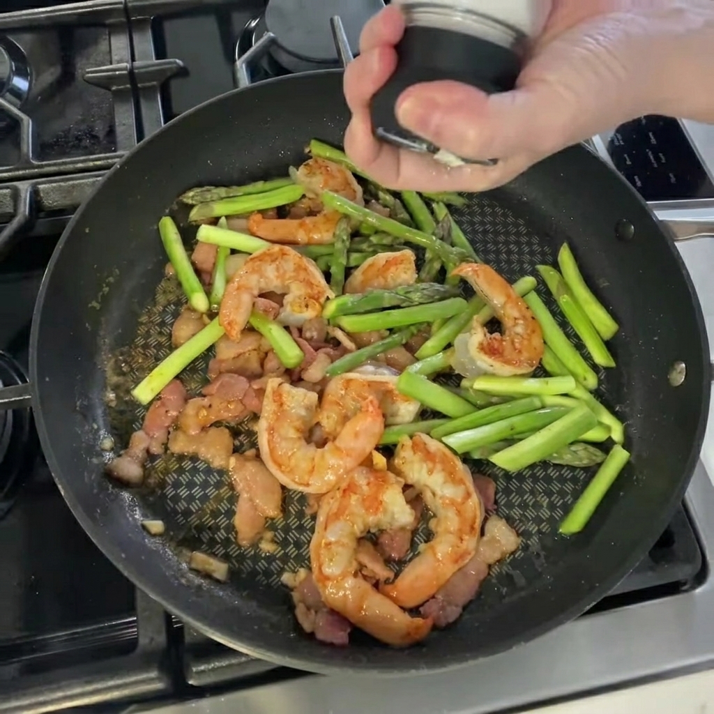 Main ajoutant du sel et du poivre sur le mélange dans la poêle.