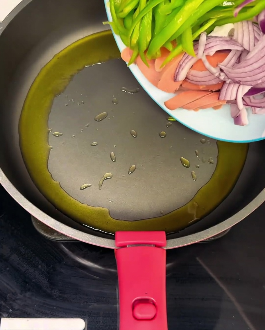 Poêle chaude avec jambon, poivrons verts et oignons sautés dans lhuile.