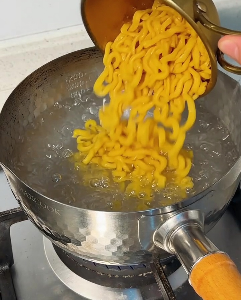 Des macaronis versés dans une casserole deau bouillante à gros bouillons.