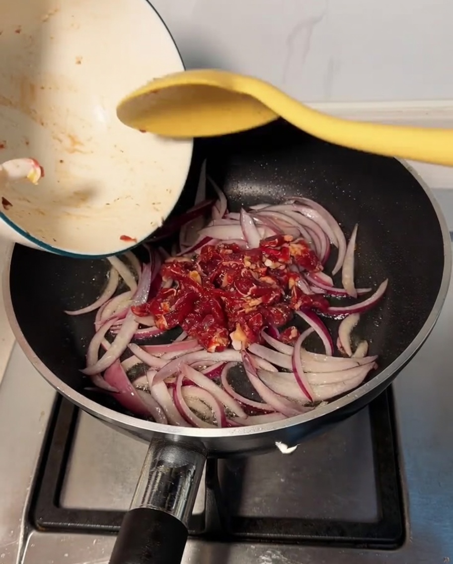Bœuf mariné ajouté dans la poêle et mélangé aux oignons ramollis.