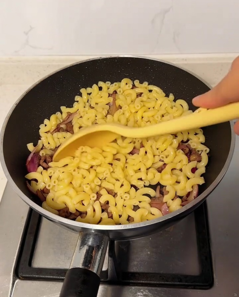 Macaronis cuits incorporés dans la poêle avec le mélange de bœuf et doignons.