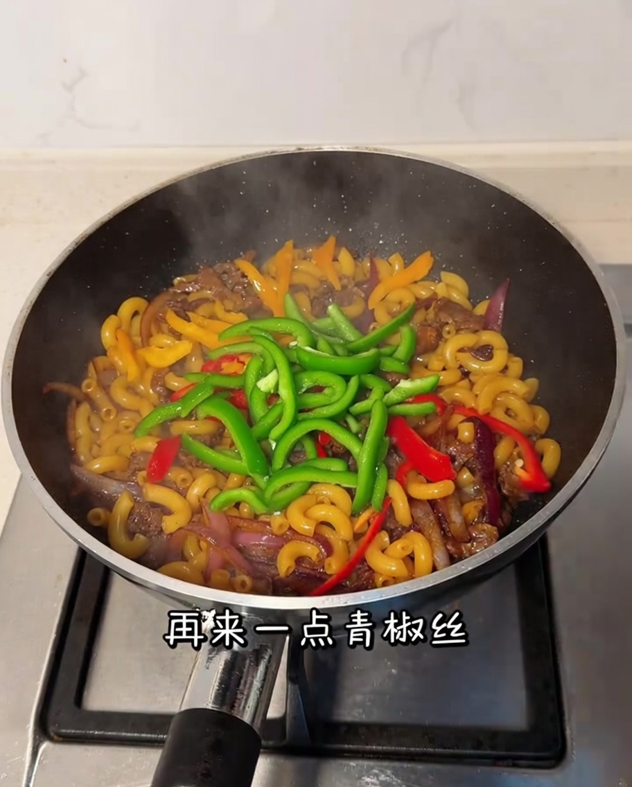 Poivron vert émincé mélangé dans la poêle avec les macaronis et le bœuf.