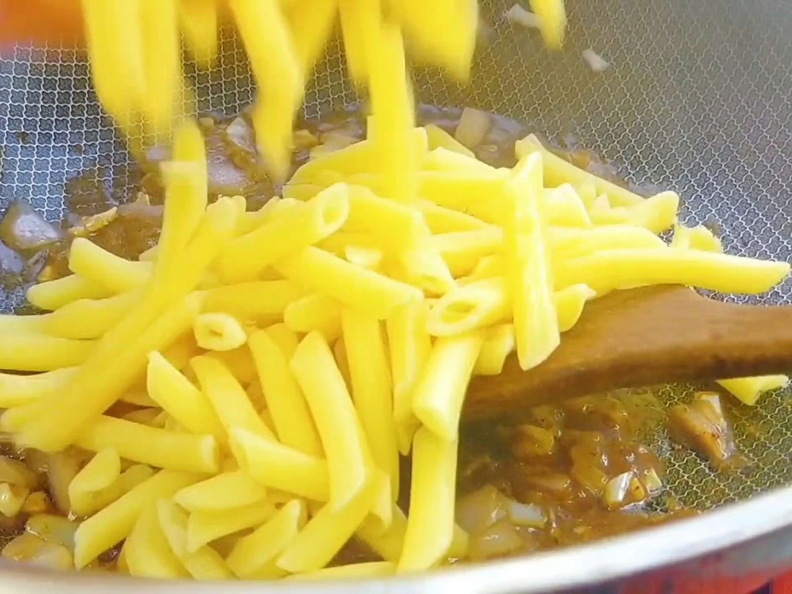 Des pennes égouttées ajoutées dans le wok contenant la base de sauce au poivre noir.