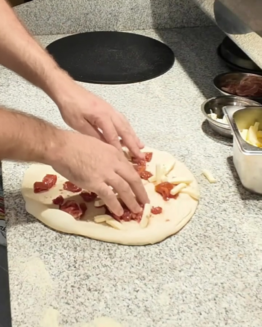 Mozzarella ajoutée sur la base de la pizza.