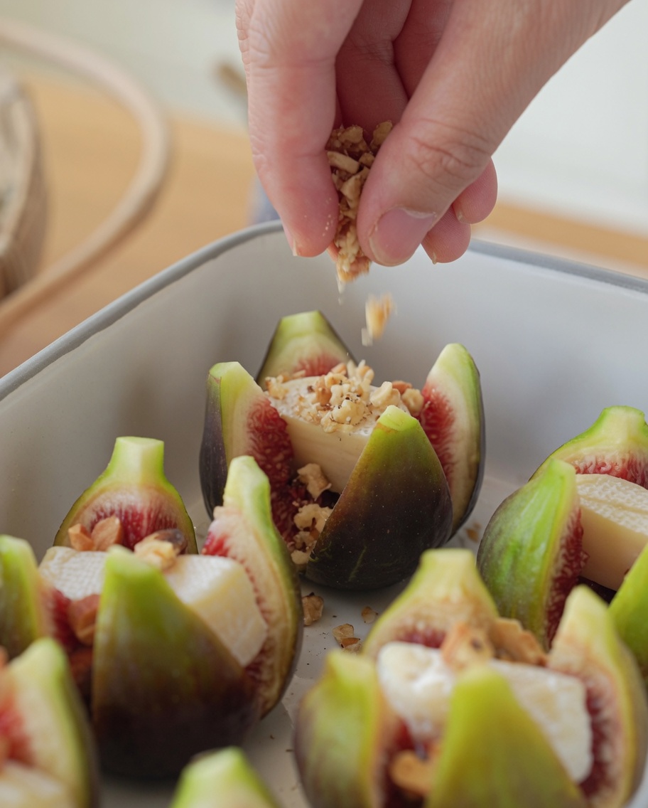 Figues farcies dans un plat de cuisson saupoudrées de noix concassées.