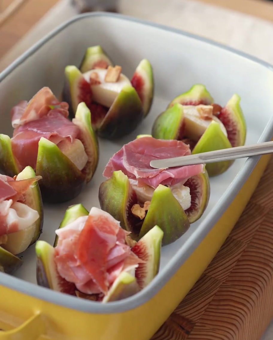 Figues farcies surmontées de tranches de jambon et de brins de romarin frais.