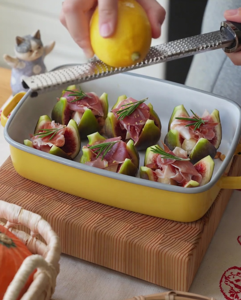 Citron frais dont on récupère le zeste au-dessus dun plateau de figues farcies au jambon.