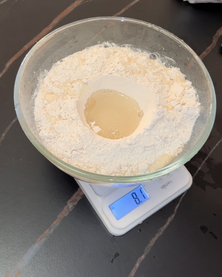 Mains en train de pétrir une pâte à pizza souple dans un bol en verre.