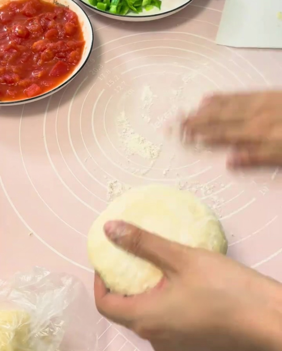 Pâte à pizza étalée sur un tapis en silicone rose.