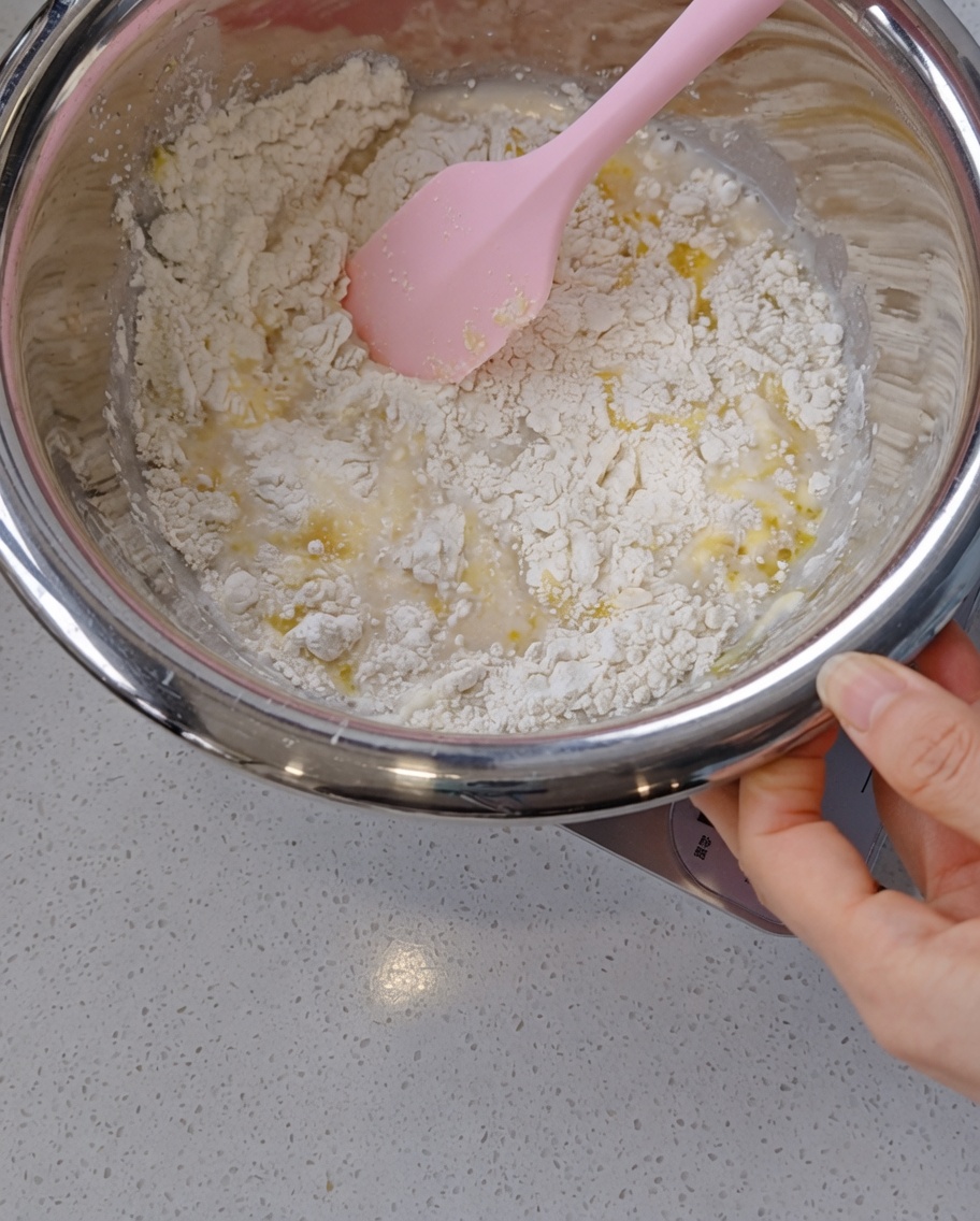 Une main utilisant une spatule en silicone pour mélanger la pâte.