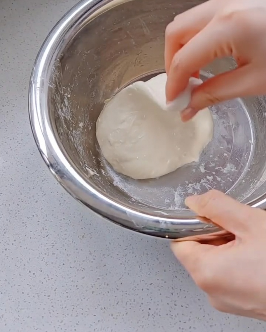 Une main étirant la pâte devenue très élastique.