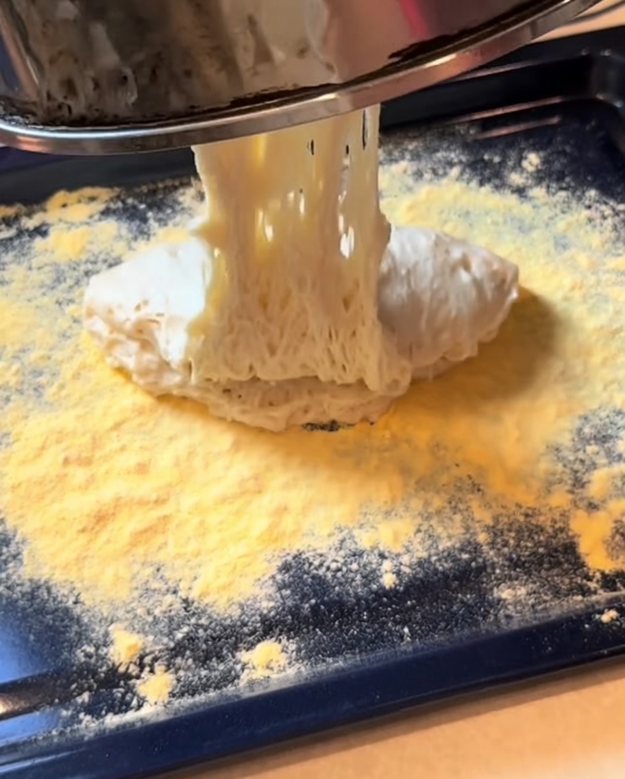 Pâte à pizza fermentée façonnée en une base rectangulaire sur une plaque de cuisson.