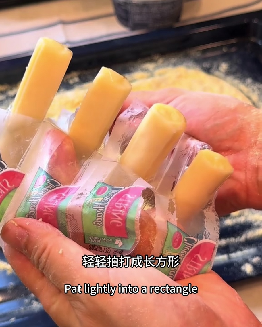Bâtonnets de mozzarella disposés sur le pourtour de la pâte à pizza rectangulaire.
